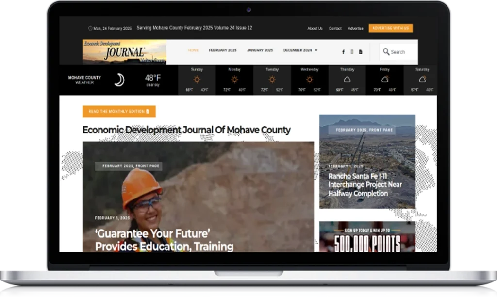 A laptop displays the Economic Development Journal of Mohave County website, featuring a headline about education and training, weather updates, navigation tabs, and an image of a person in an orange hard hat.