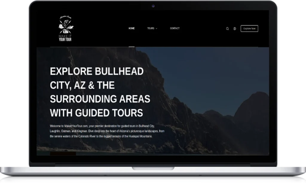 A laptop displays a website homepage for Mojave Tour Co. The screen shows a mountainous landscape and large white text promoting guided tours in Bullhead City, Arizona, and nearby areas.