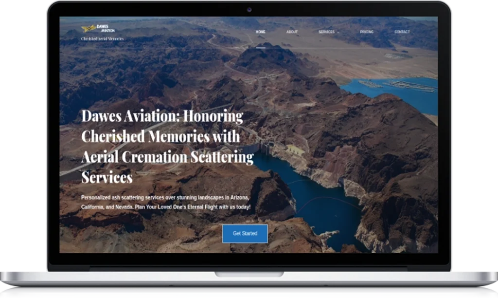 A laptop screen displays the Dawes Aviation website, featuring a headline about aerial cremation scattering services and a background image of a rugged canyon landscape with a river and mountains.