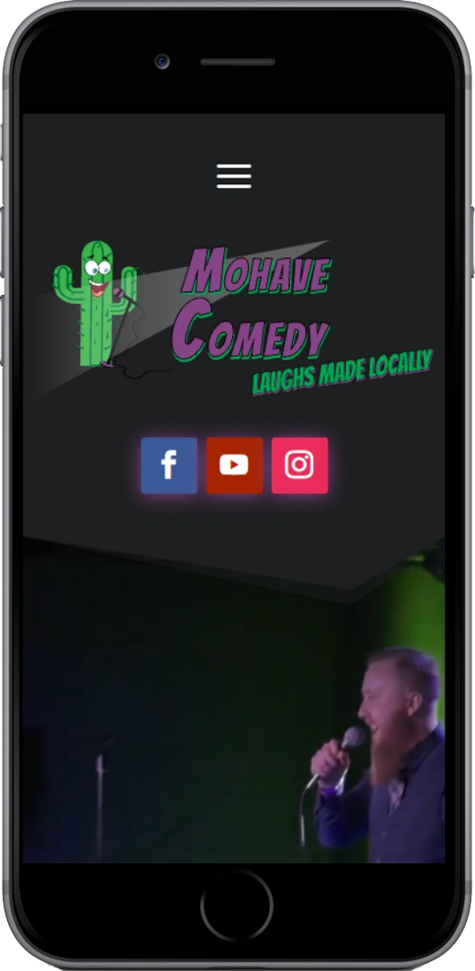 A smartphone screen displays the Mohave Comedy website homepage, featuring a cactus logo, slogan "Laughs Made Locally," social media icons, and a comedian holding a microphone on stage.